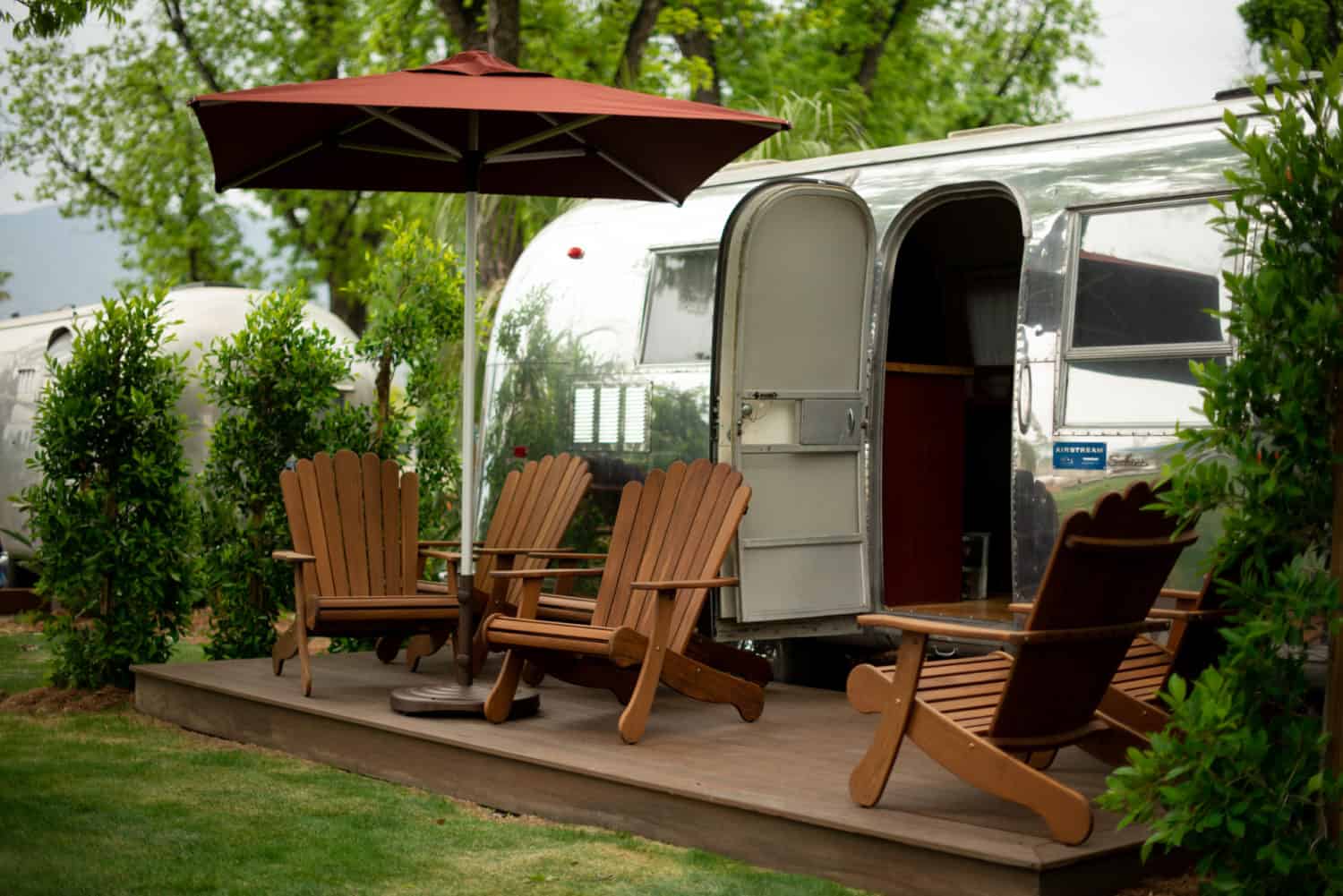 A Launch Pointe RV Resort airstream parked next to a lawn with chairs and an umbrella in California.
