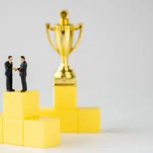 Two KEI Founder businessmen standing on top of yellow cubes with a Lifetime Achievement Award trophy.