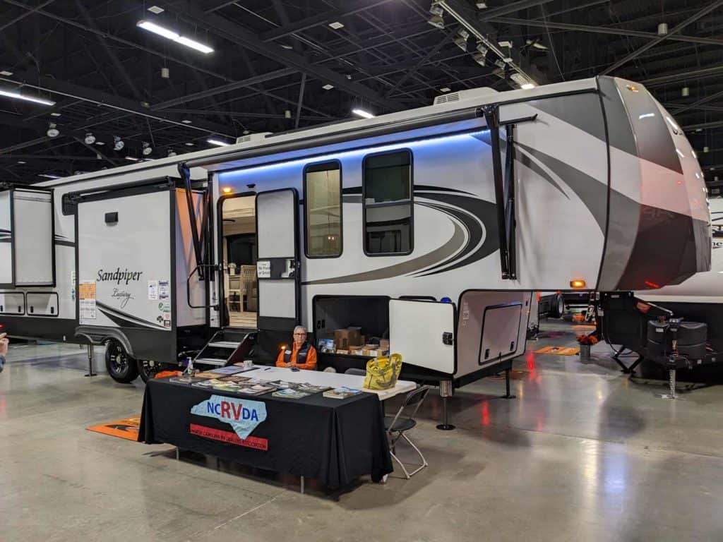 A Progressive NCRVDA Charlotte Show features an RV on display, courtesy of Country Roads RV Center.