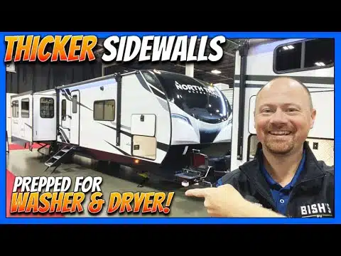 In 2023, a man is roughing it in style by proudly pointing to his RV with the words "thicker sidewalls".