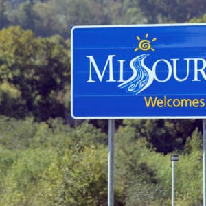 Missouri welcome sign surrounded by trees, featured in the Official RV & Camping Guide.