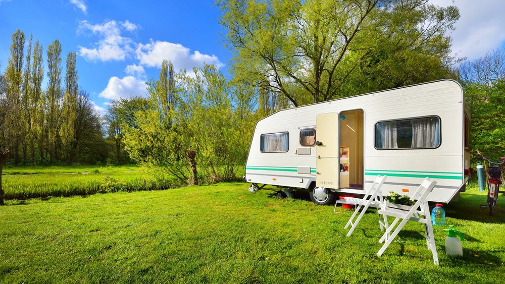 A LeadingCampings camper trailer parked on a grassy field in Europe during the Camping Boom.