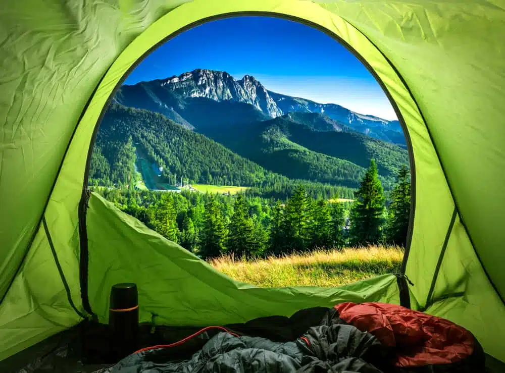 A green tent with a view of mountains in Europe.