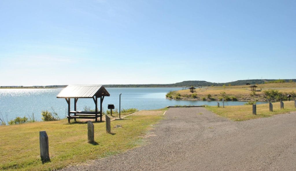 A road leading to Stillhouse Hollow Lake, managed by the U.S. Army Corps of Engineers within the Fort Worth District, featuring a picnic table.