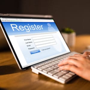 A person open registration on a laptop with the word register on it for the 32nd Annual event.