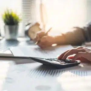 A man is using a calculator at a desk to support Virginia taxpayers with outdoor rec expenses.