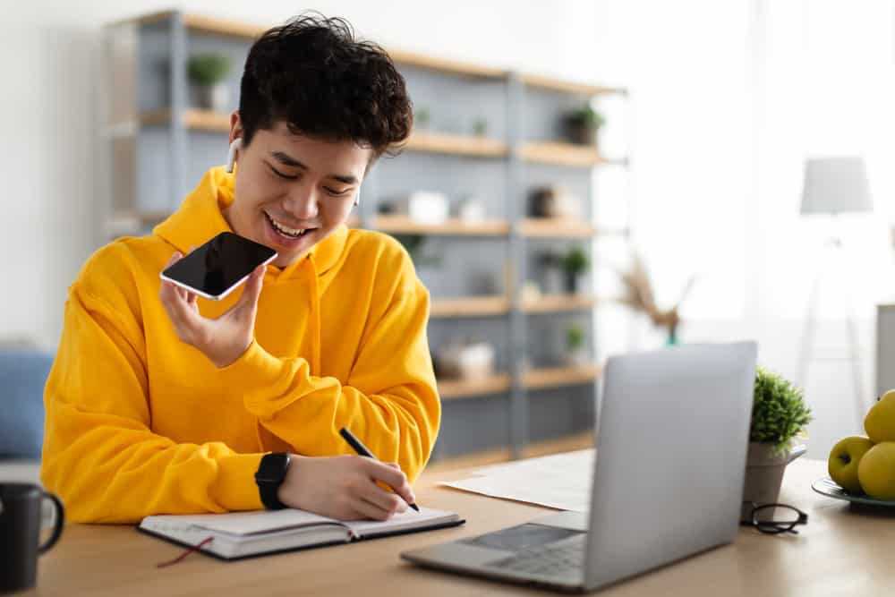 A man in a yellow hoodie is sitting at a desk with a laptop providing RV technical support.