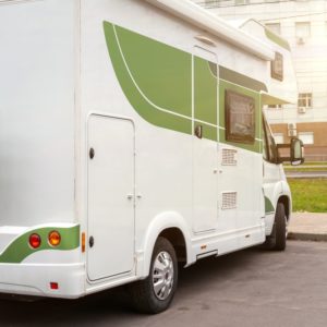 A white and green RV parked in front of the City of Quesnel building.