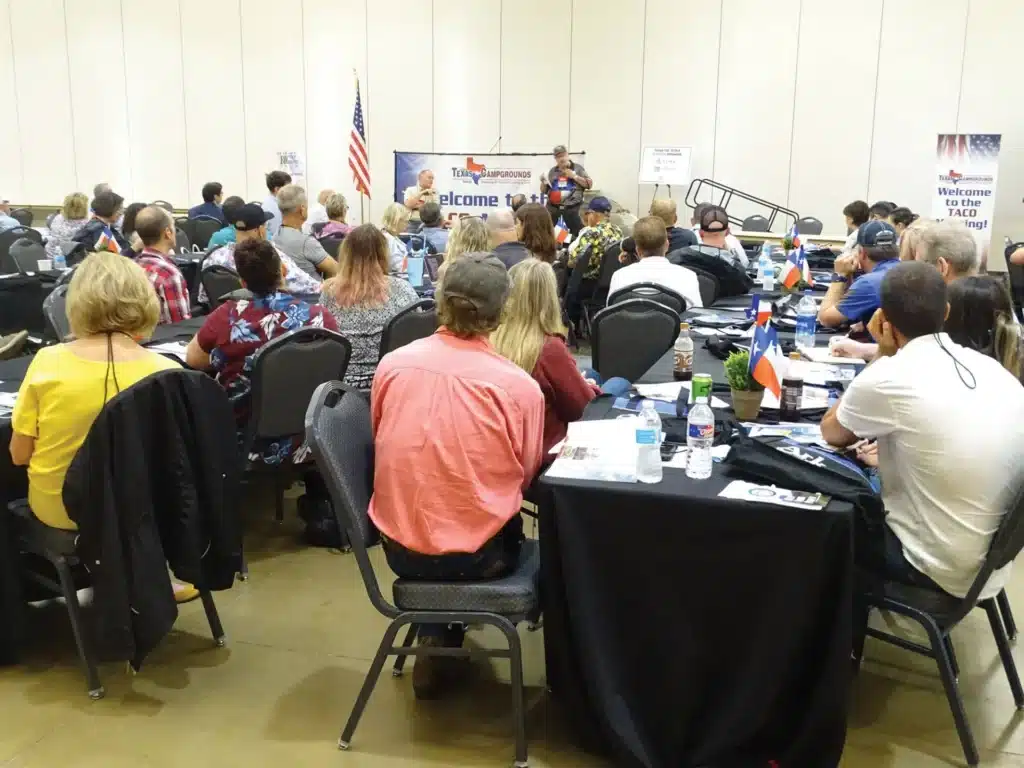 A group of people sitting at tables in a conference room during a Tradeshow Spring Meeting.