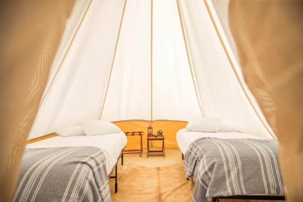 A cozy bed in an Under Canvas tent, adorned with a soft blanket.