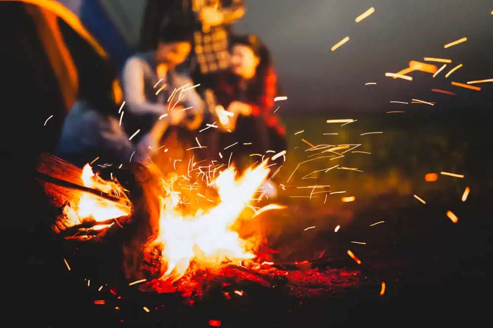 A group of people sitting around a campfire at night in Yogi Bear's Jellystone Park.