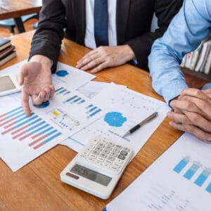 Two business people from the IVEE Group team sitting at a table and analyzing financial graphs.