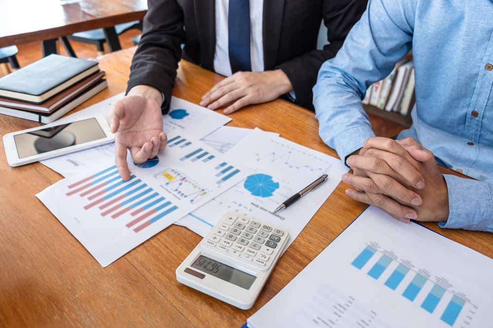 Two business people from the IVEE Group team sitting at a table and analyzing financial graphs.