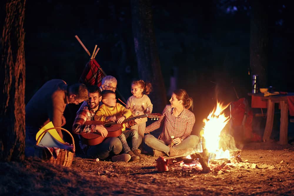 Steve Stafford, Director of Franchise Sales at Yogi Bear's Jellystone Park, overseeing a group of people sitting around a campfire at night.