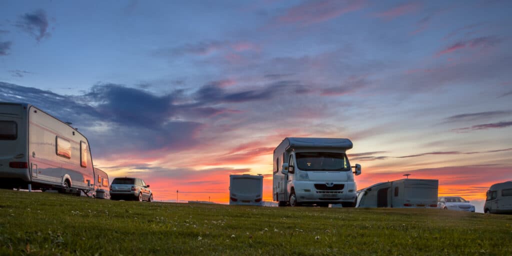 A group of RVs parked in a field at sunset, showcasing the 31st Annual Northwest Michigan RV Camping Show.