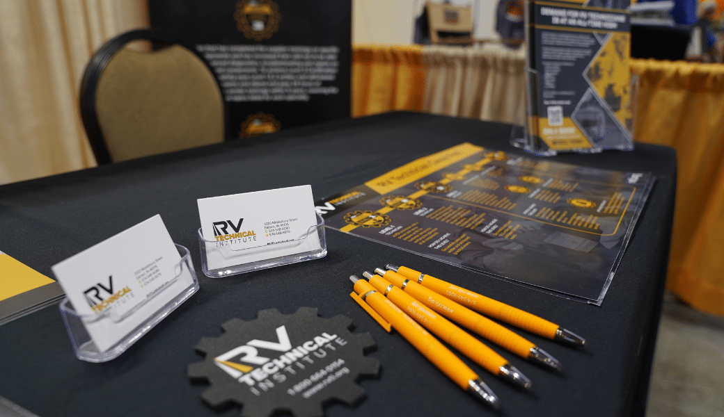 A table set up with business cards and pens promoting the RVTI RV Technician Training Program.