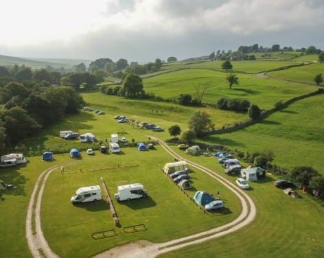 An aerial view of a campsite nestled in the Yorkshire Dales, surrounded by breathtaking nature.