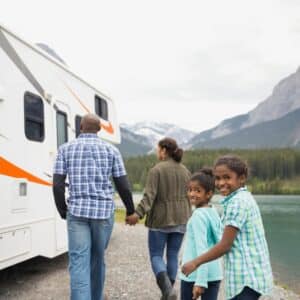 Family standing next to an RV in front of a lake, enjoying their Q1 2023 Results with Sun Communities that have exceeded expectations.