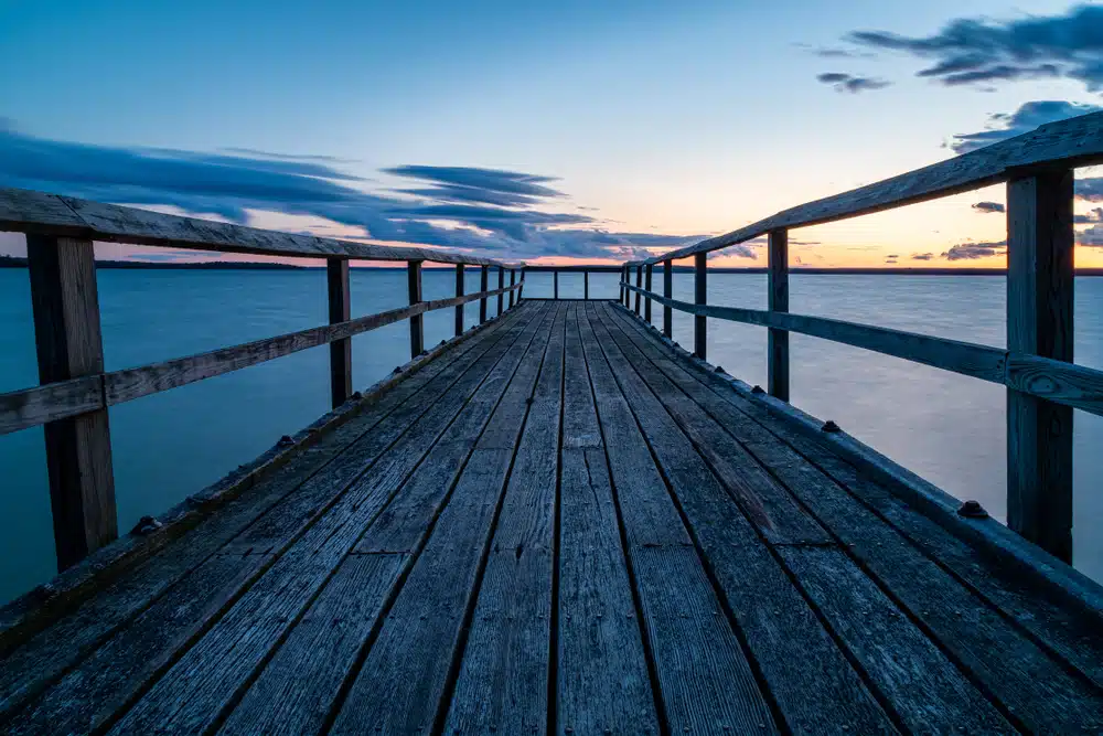 A wooden pier at Aloha State Park, in the water during a stunning sunset.