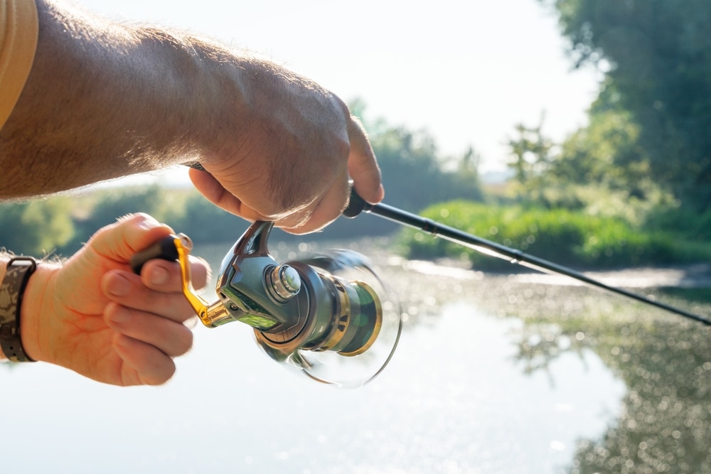 A man is holding a fishing rod and reel by the Forest Lake Dam, authorized by FERC.