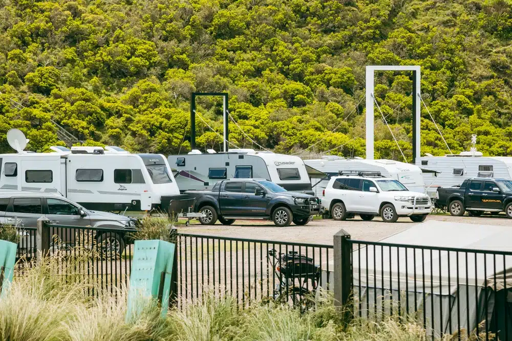 A cluster of caravans parked alongside a fence, providing accommodation amidst an ongoing crisis.