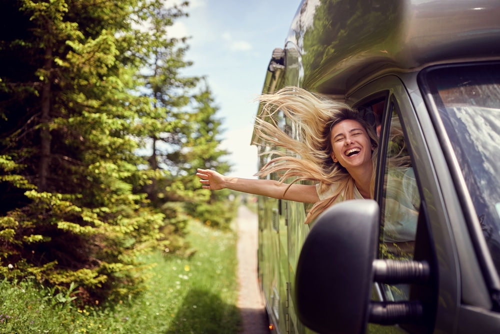 A woman is waving out of the window of an affordable RV rental.