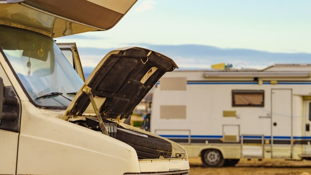 Two rvs parked in a field with the hood open as part of Tyson Watkins' Comprehensive Training Program at RVTI.