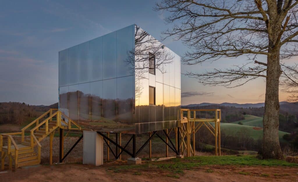 A luxury metal building sits on top of a hill, surrounded by nature.