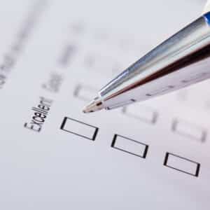 A person filling out a RVDA Dealer Satisfaction Index Survey form with a pen.