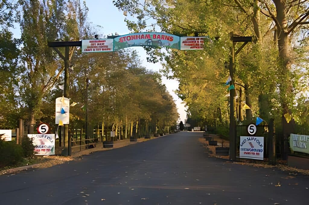 The entrance to Stonham Barns Park, offering leisure opportunities surrounded by trees and informative signs.