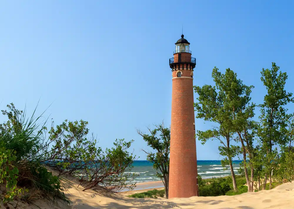 A lighthouse sits on top of a sand dune overlooking Silver Lake.