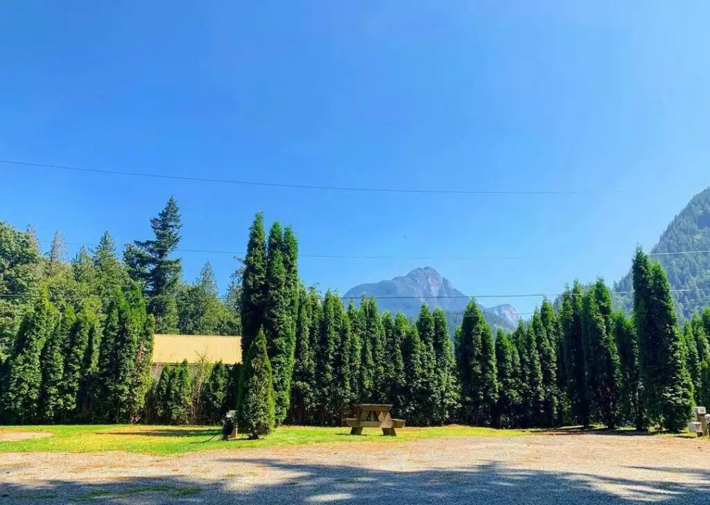 A parking lot with trees and mountains in the background near WildRose Campground in Hope BC.