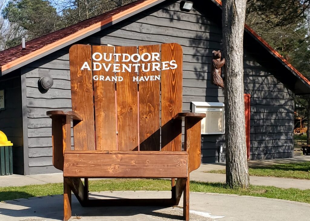 An outdoor adventures campground featuring an adirondack chair in front of the Grand Haven Resort's Camp Store building.