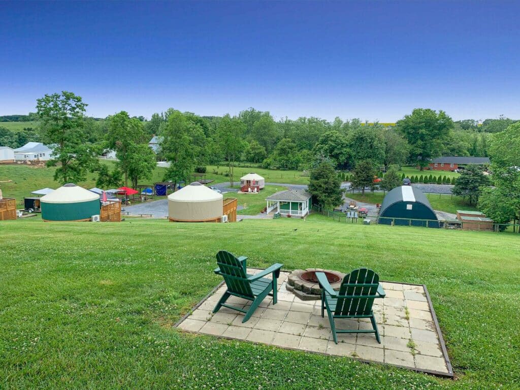 Yurts at Spacious Skies Campgrounds, featuring seasonal camping discounts, offer breathtaking views on a hilltop overlooking a sprawling field.