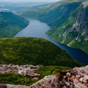 A view from the top of a mountain overlooking a lake, showcasing Newfoundland and Labrador's Tourism Industry.