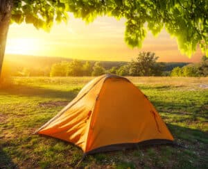 Campers set up a tent in a picturesque New England field at sunset, providing insights into the beauty of outdoor adventures.