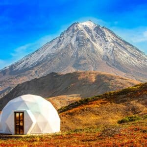 Two white tents set up in front of a stunning mountain, creating an idyllic glamping experience amidst the outdoors.