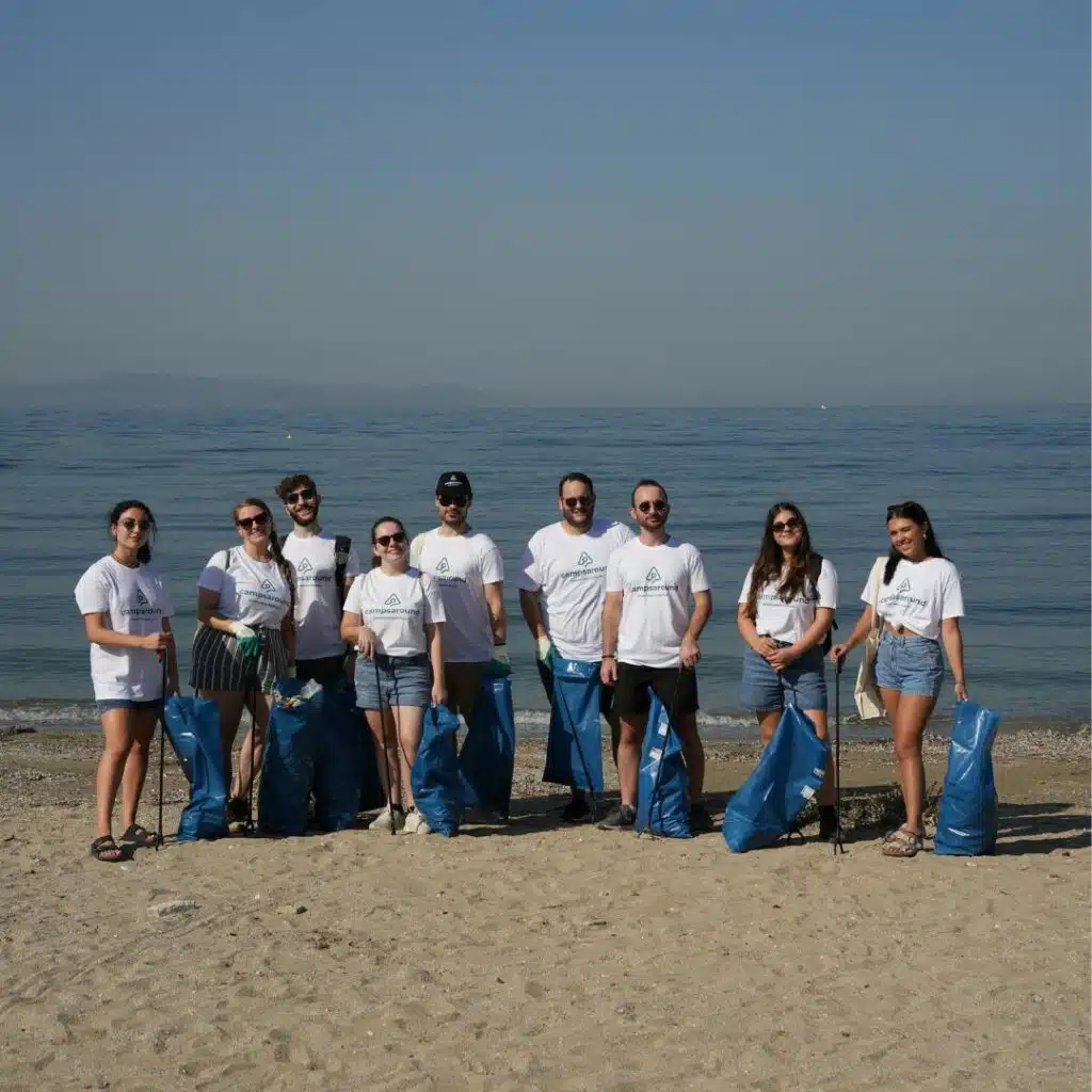 A group of people participating in an Environmental Initiative on World Cleanup Day, standing on a beach with garbage bags.