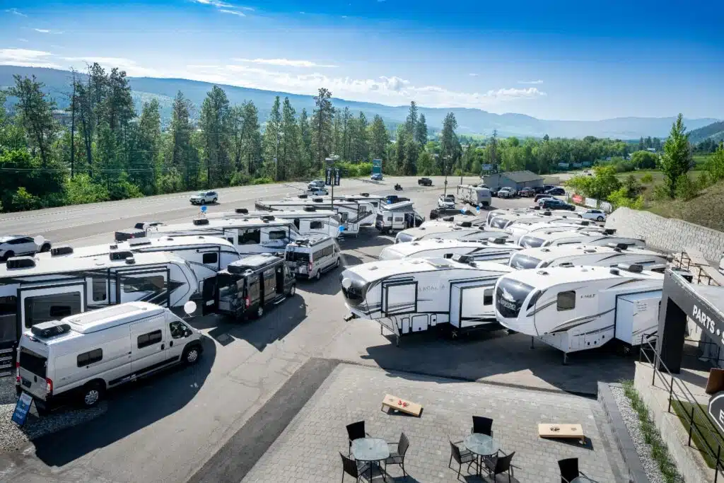 Numerous RVs parked in a parking lot with mountains in the background, showcasing the charitable milestone achieved by Voyager RV Centre amassing CA$100K.