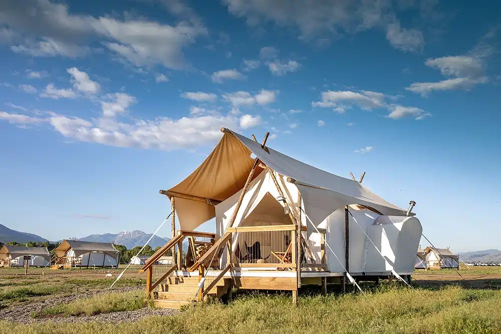 A tent in the middle of a field with mountains in the background, featured in Sunset Magazine's 2023 Travel Awards.