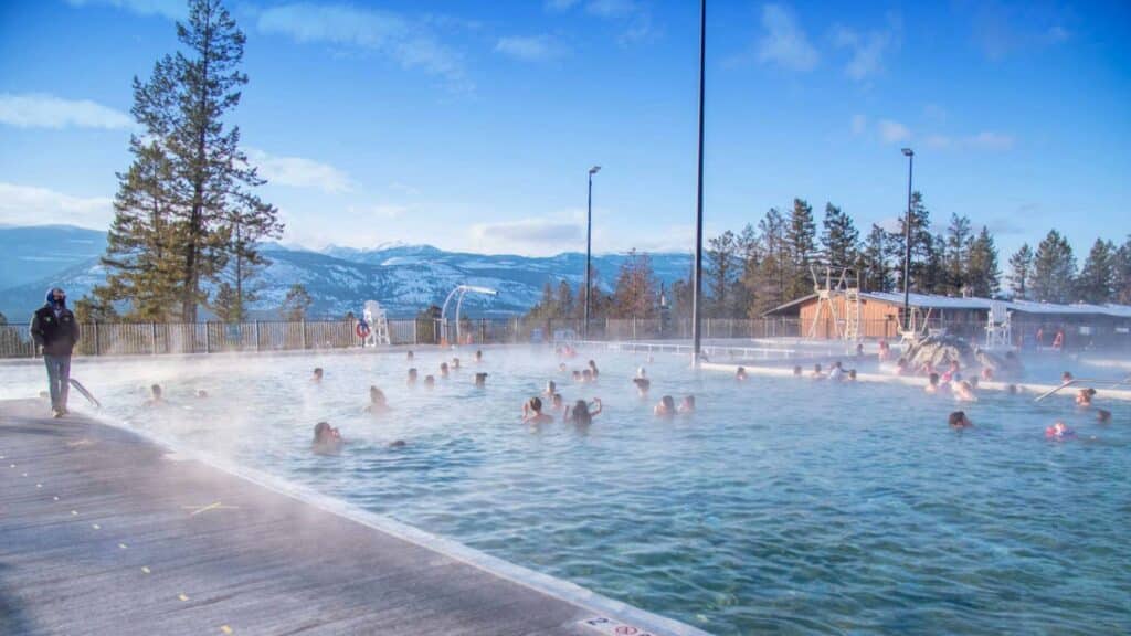 A group of people are swimming in a hot spring at an RV Resort.