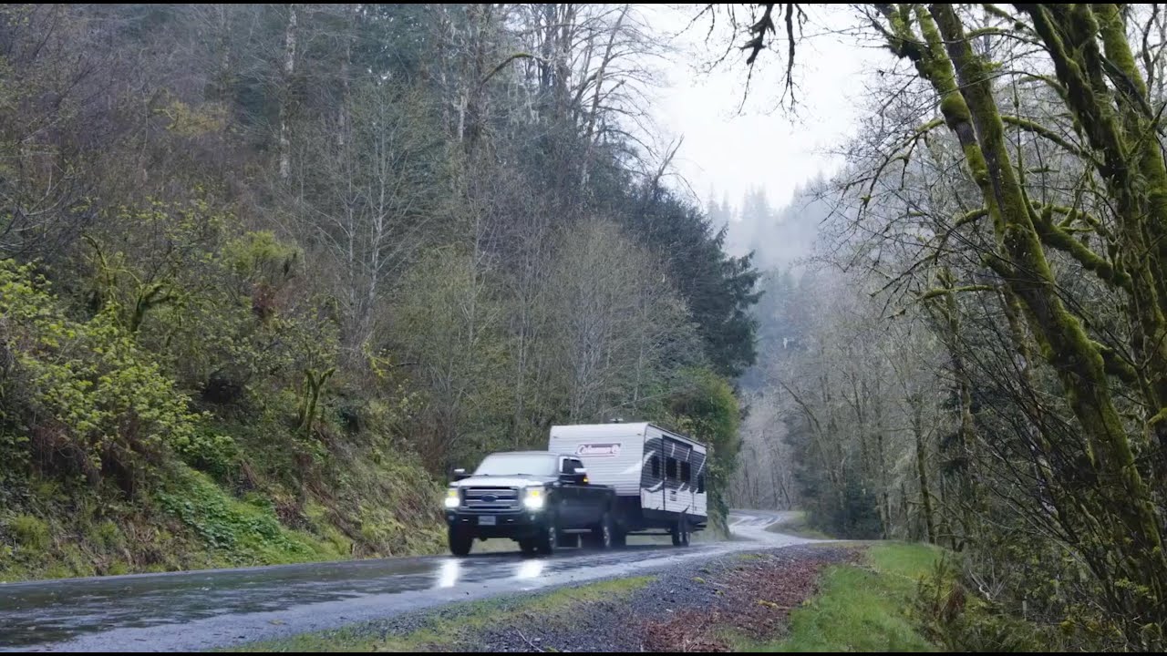 An RV cruising along an open road, braving the rain.