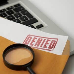 A magnifying glass over a Glamping Site document with the word denied.