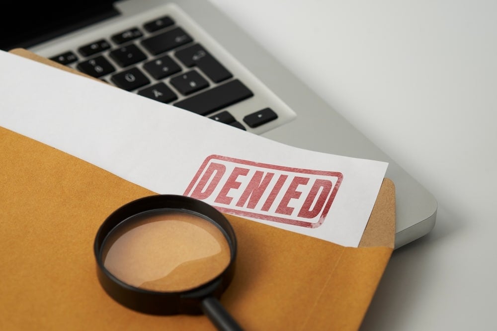 A magnifying glass over a Glamping Site document with the word denied.