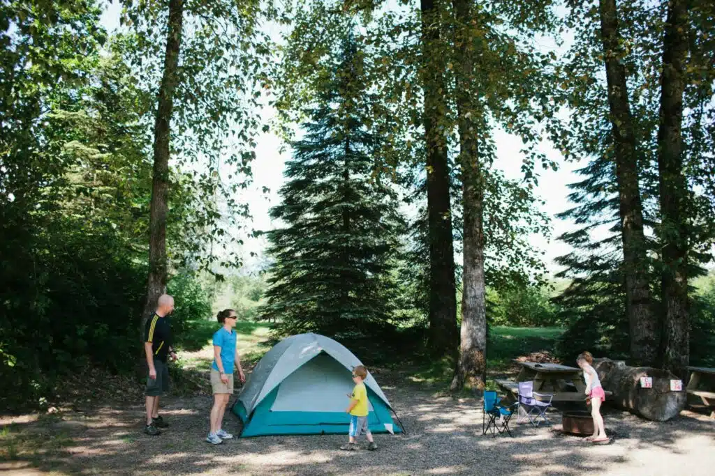 A group of people standing around a tent in the Vedder River Campground.