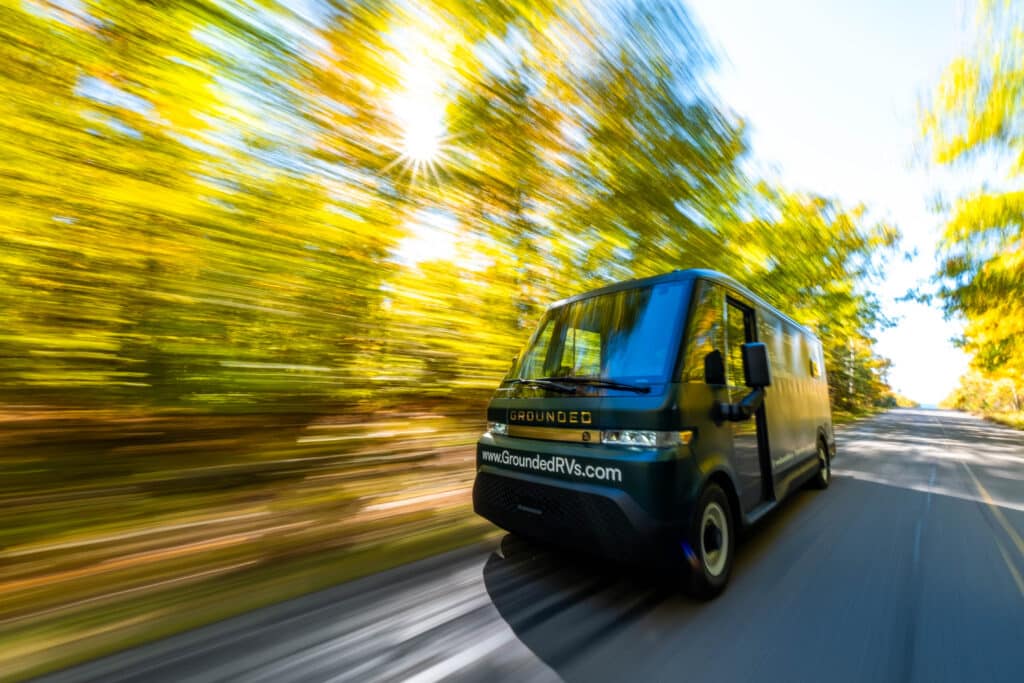 A G2 electric RV van driving down a road with trees in the background.