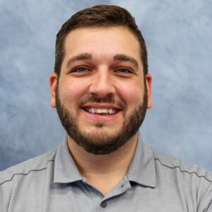 A man with a beard smiling for the camera during MC Fireside Chats on October 25th, 2023.