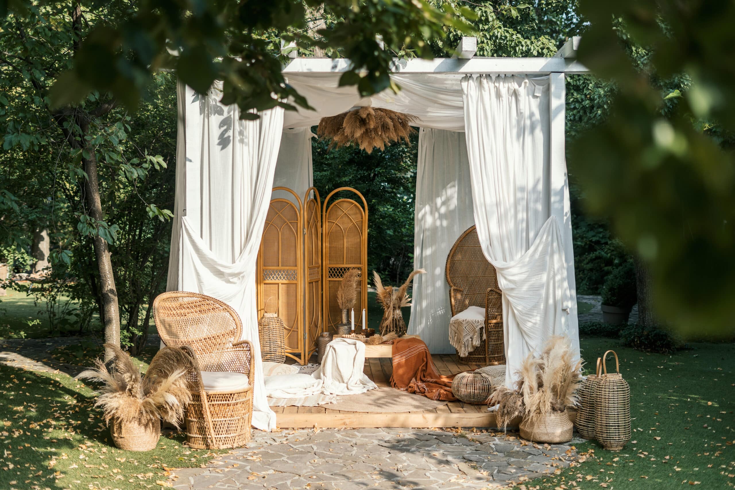 Timber Valley Retreat,Glamping,Wedding Experience is enhanced by a white gazebo adorned with wicker baskets and rattan chairs in a park.