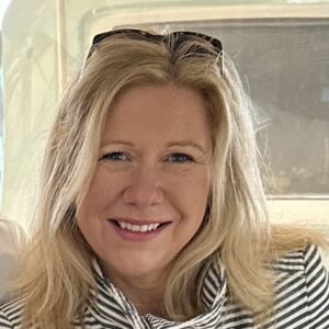 A woman is smiling while sitting on a boat during the MC Fireside Chats on February 28th, 2024.