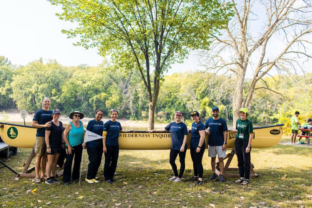 A group of people posing in front of a Winnebago Industries canoe.